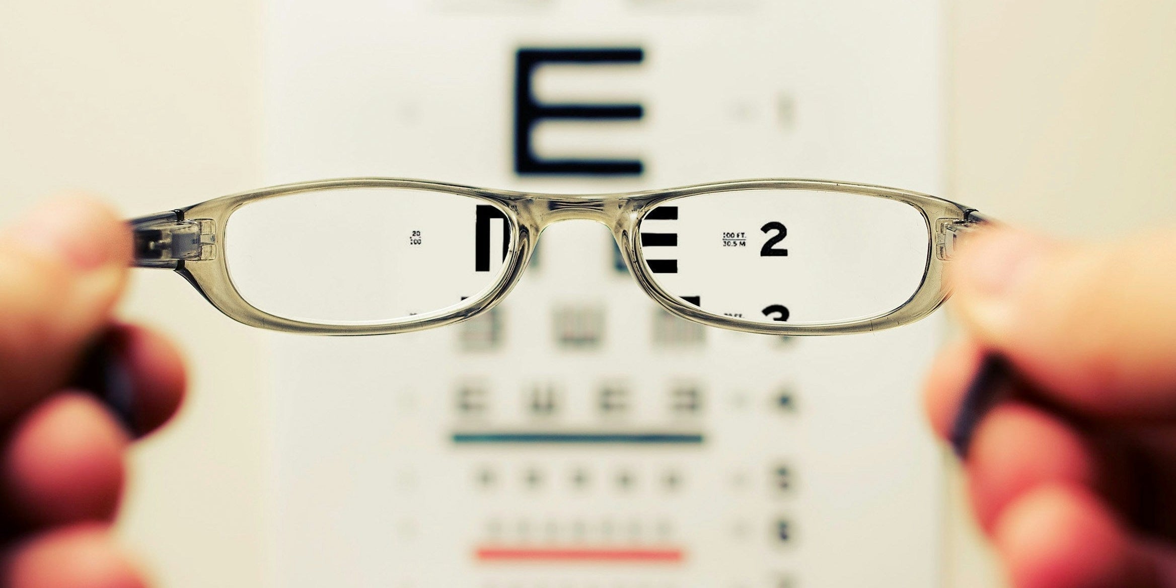 Eyeglasses held up to an eye test chart