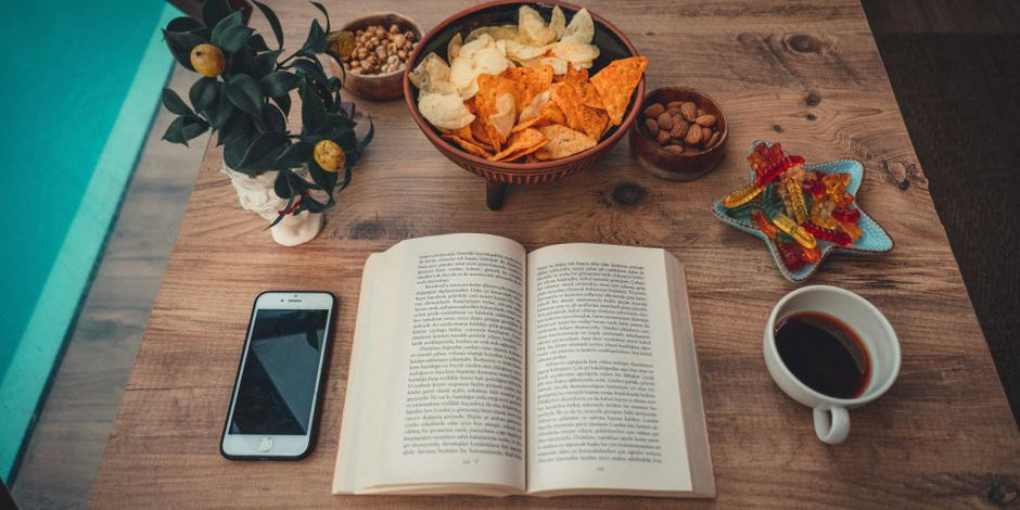 Open book with snacks and coffee on table