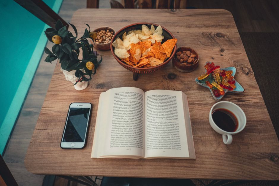 Open book with snacks and coffee on table
