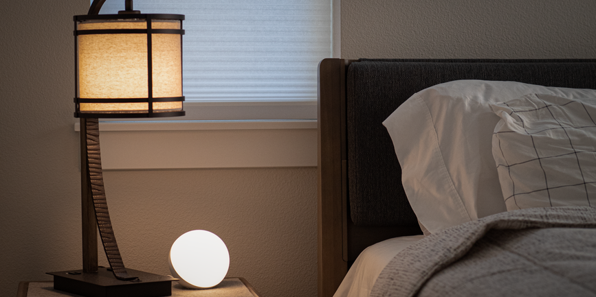 Lamp and glowing orb beside bed
