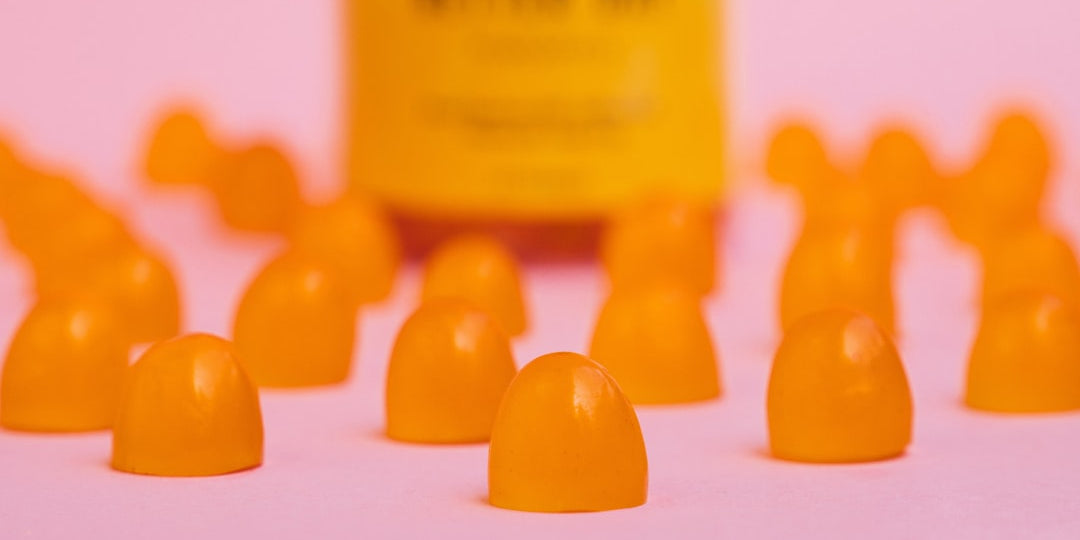 Several orange gummy vitamins with bottle