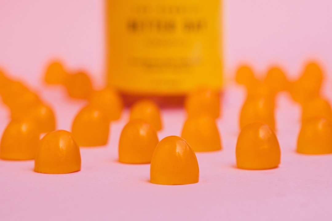 Several orange gummy vitamins with bottle
