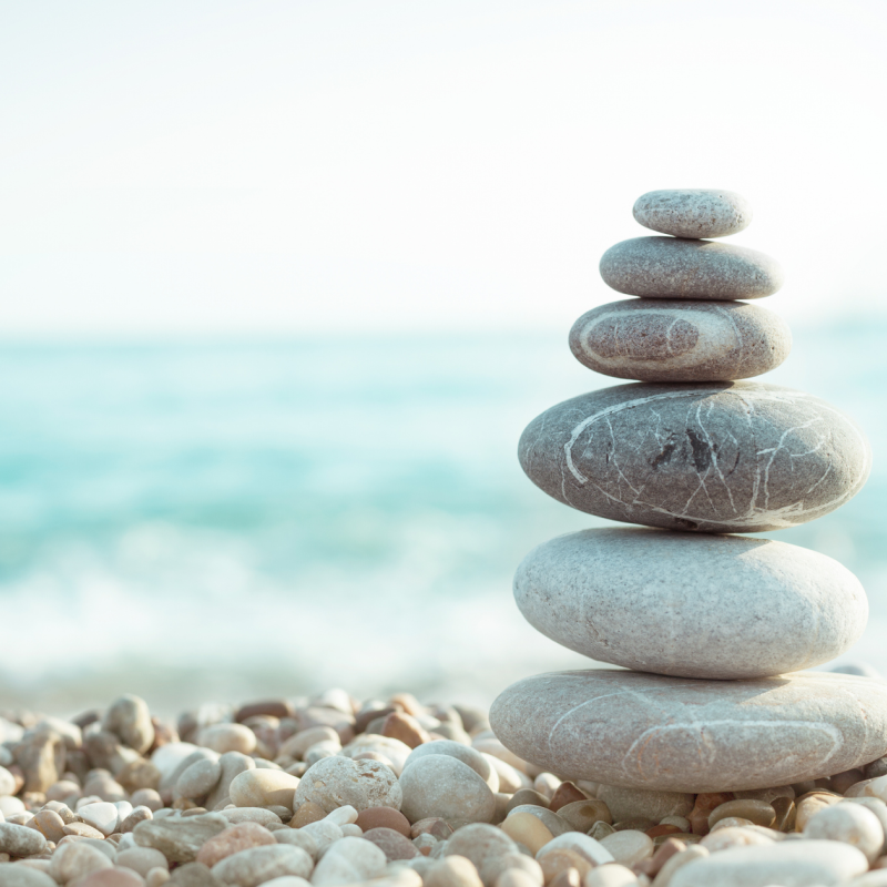 Smoothly stacked gray stones balanced on pebbles by serene ocean