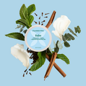 Product Image for Charlotte's Web Balm container surrounded by mint leaves, cinnamon sticks, and flowers on a blue background