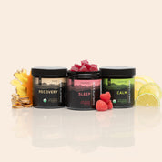 Product Image for Three jars of CBD gummies Recovery, Sleep, and Calm arranged with ginger, raspberries, and citrus on a neutral background.