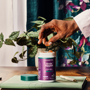 Product Image for Person holding a supplement capsule next to a container labeled &#39;Brain Support&#39; on a table with a plant in the background.