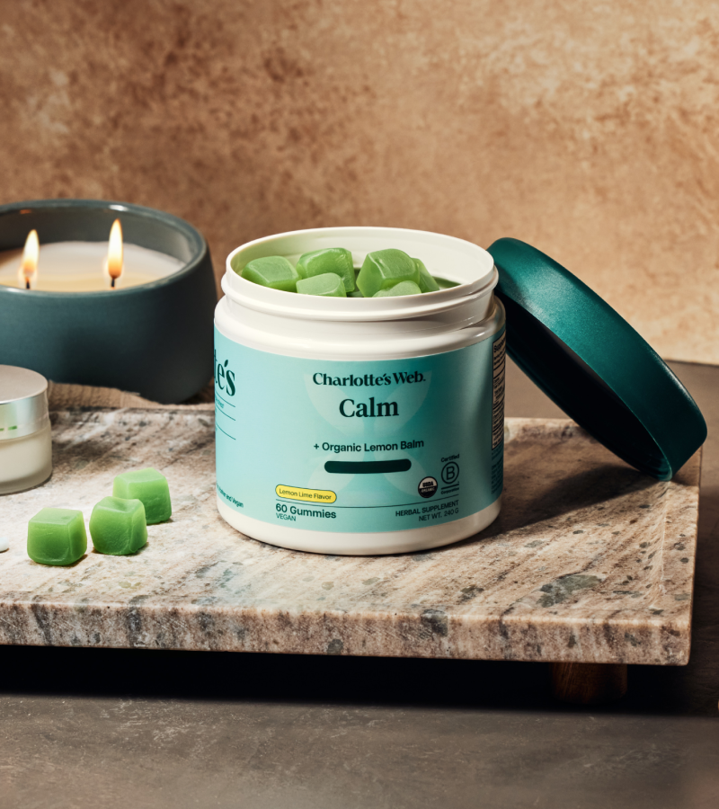 Jar of Charlotte's Web Calm gummies on a marble surface with candles in the background