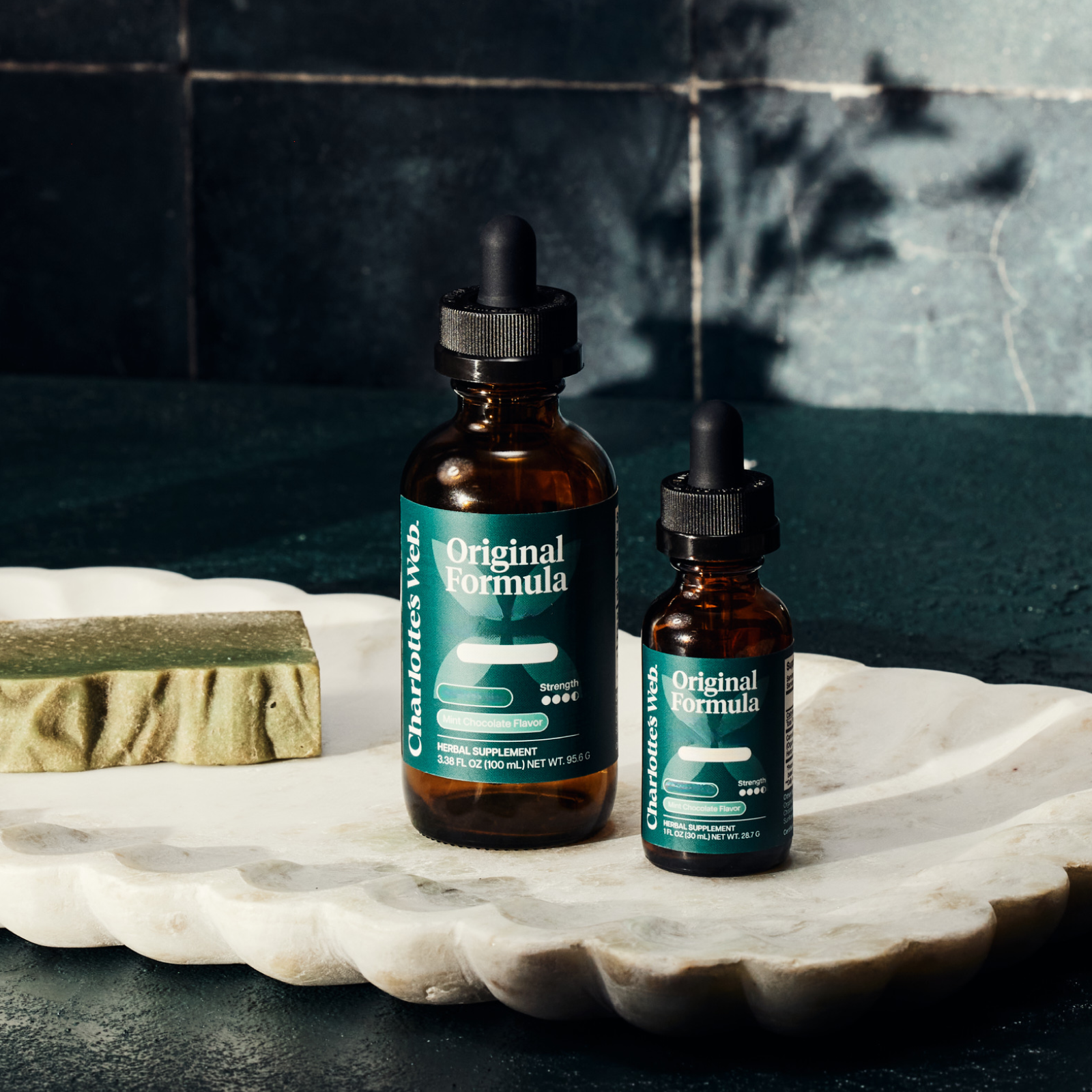 Product Image for Two bottles of &#39;Original Formula&#39; on a marble surface with a dark tiled wall background.