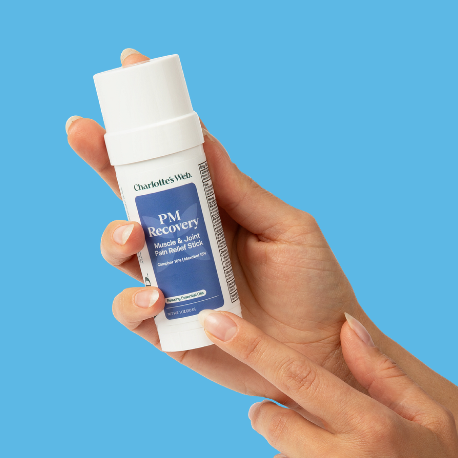 Hand holding a Charlotte's Web PM Recovery product against a blue background