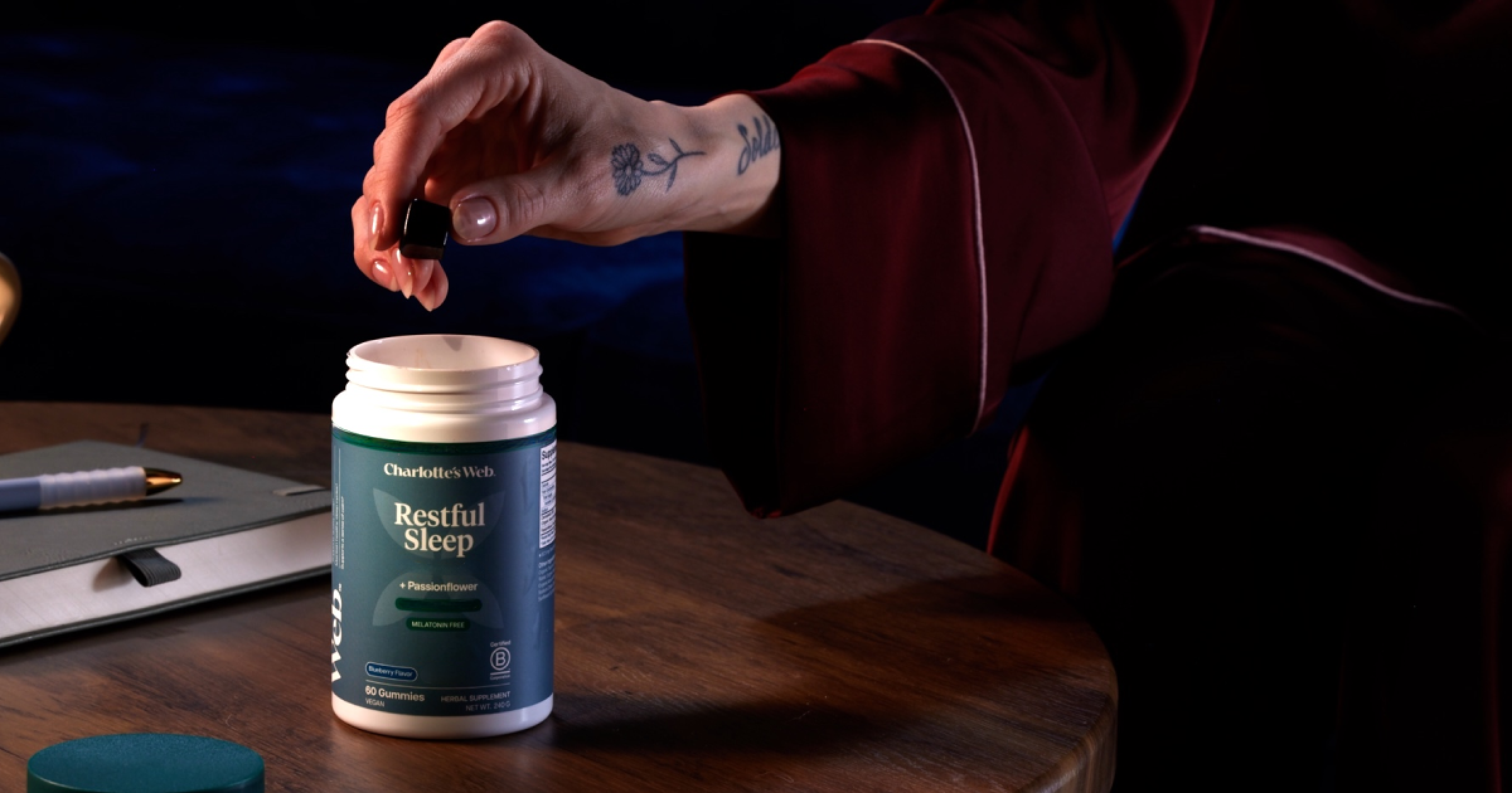 Person opening a bottle labeled 'Restful Sleep' on a wooden table.