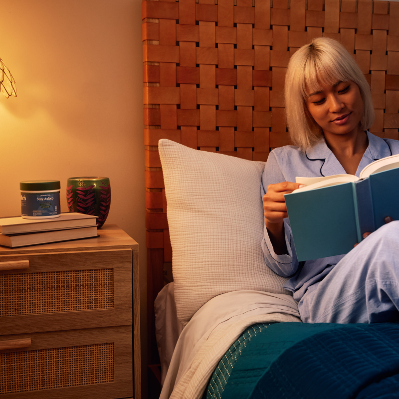 Woman reading a book in bed with a warm, cozy ambiance