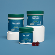 Product Image for Three containers of &#39;Stay Asleep&#39; supplement by Charlotte&#39;s Web on a blue background.