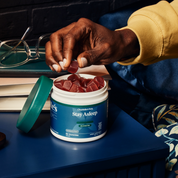 Product Image for Person holding a supplement container labeled &#39;Stay Asleep&#39; with gummy supplements on a desk.