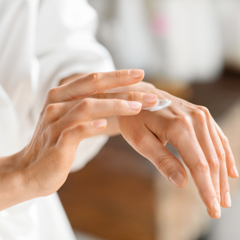 Person applying cream to their hand with a blurred background