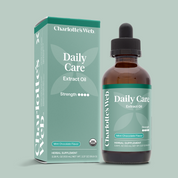 Product Image for Charlotte's Web Daily Care Broad-Spectrum Extract Oil shown with its mint green packaging box and an amber glass dropper bottle on a solid sage green background.