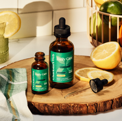 Product Image for Two bottles of &#39;Daily Care&#39; supplement on a wooden surface with lemons and a towel.