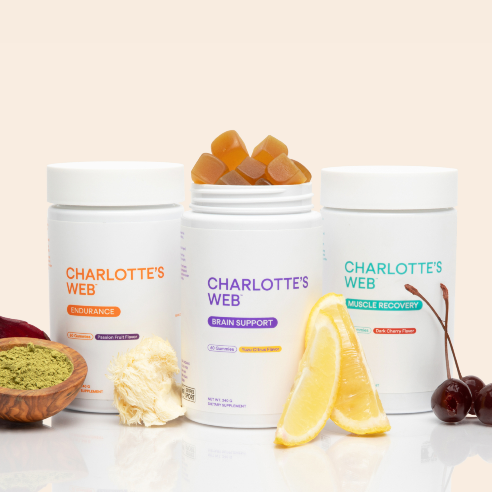 Three containers of Charlotte's Web products with gummies, lemon slices, and cherries on a light background.