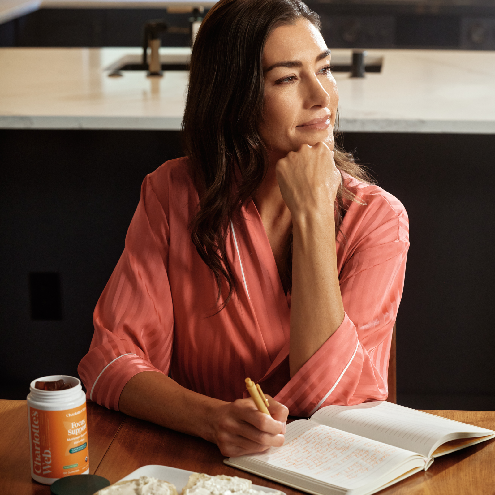 Product Image for Woman in pink robe sitting at a table with an open book and a container of protein powder.