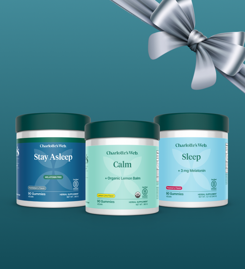 Three Charlotte's Web gummy containers with a silver bow on a teal background