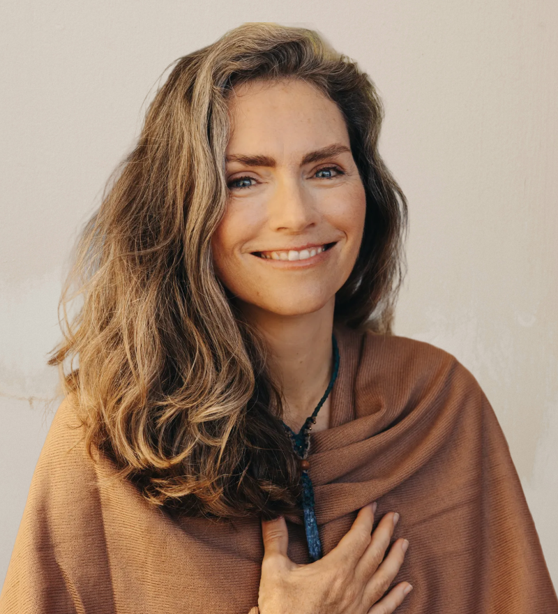 Woman wearing a brown shawl against a plain background