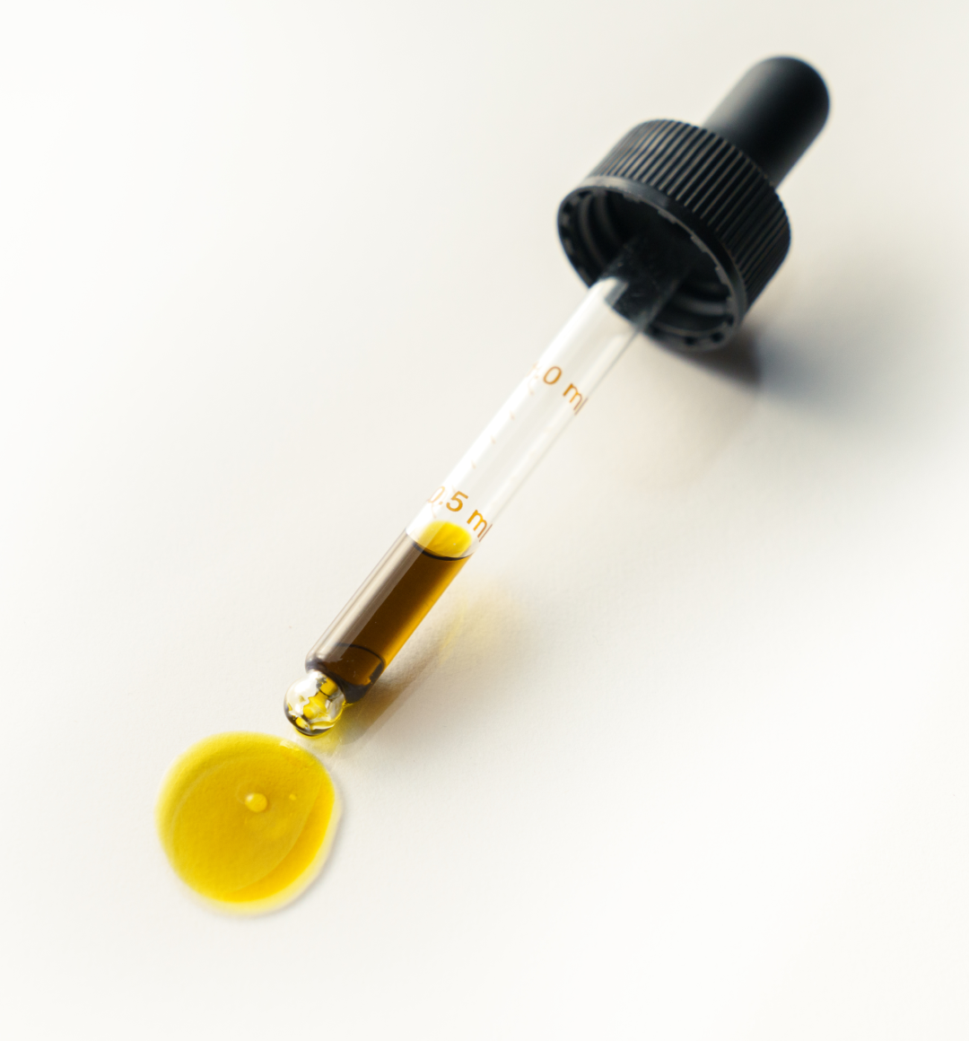 Vial with dropper and yellow liquid on a white background