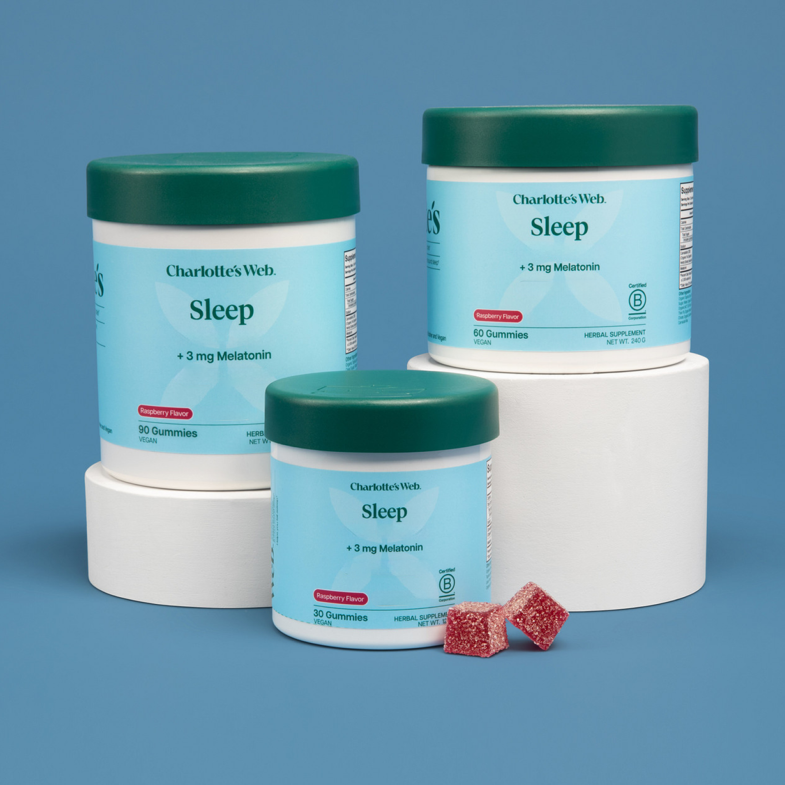 Product Image for Three containers of Charlotte's Web Sleep Gummies with sugar-coated gummies on a blue background