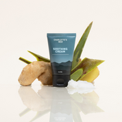 Product Image for Tube of Charlotte&#39;s Web Soothing Cream with aloe vera leaves on a reflective surface