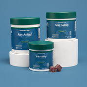 Product Image for Three containers of Charlotte's Web Stay Asleep Gummies with sugar-coated gummies on a blue background